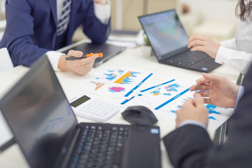 ノートパソコンと資料を前に進める社内の企画会議