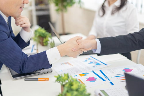 会議中に商談が決まって握手するビジネスマン