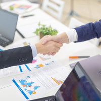 会議室での契約成立、握手を交わすビジネスマンの写真