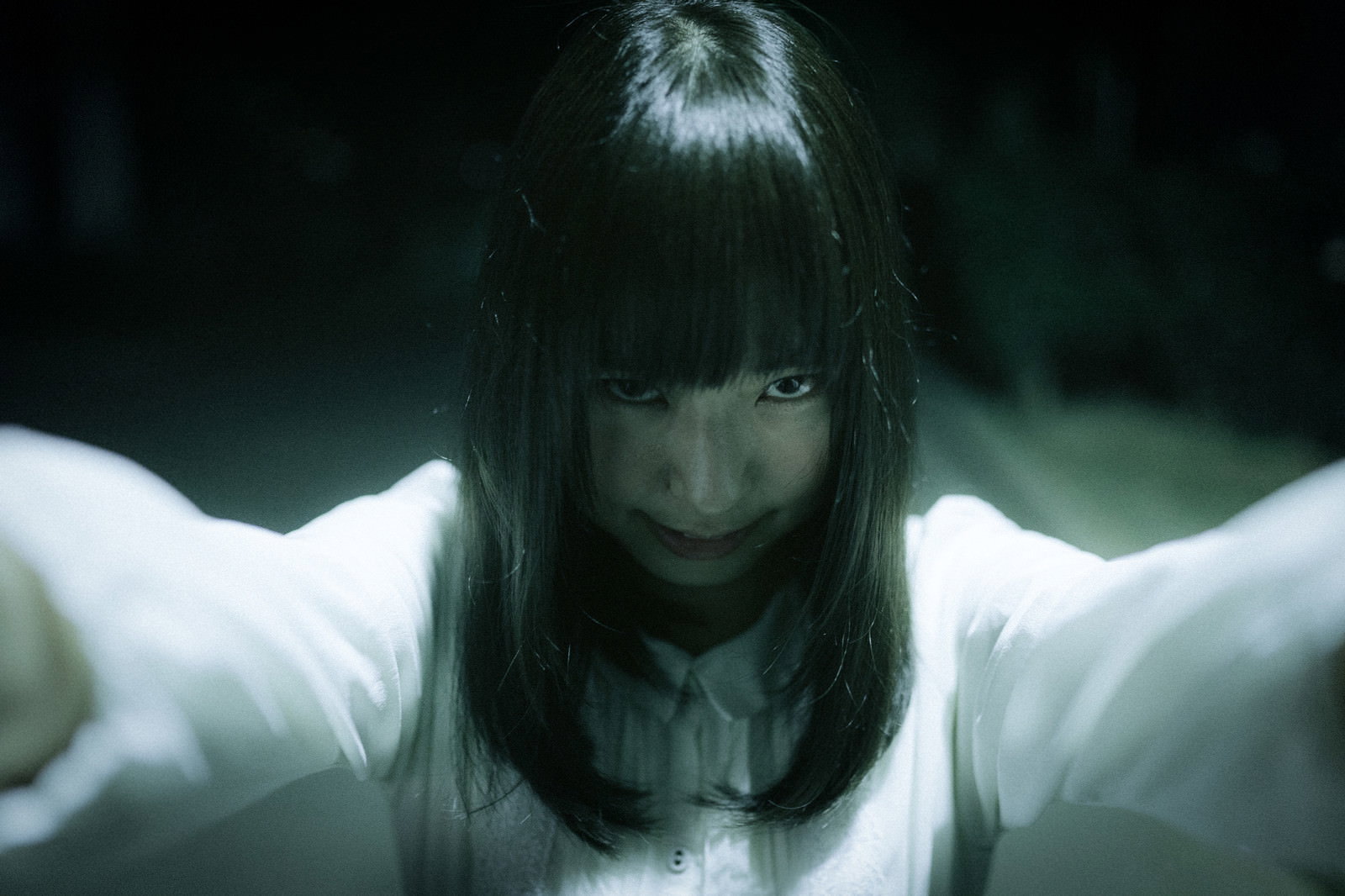 暗闇の中で束縛され絶望的な表情を浮かべる白い衣服の女性［モデル：さとうゆい］