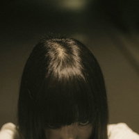 暗がりで髪で顔を隠し恨みを込める女性の不気味な表情の写真