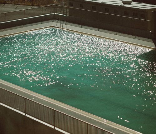 太陽光で輝く学校のプールの水面と屋内施設