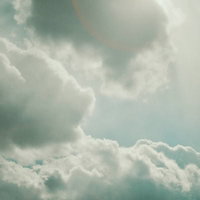 太陽に白い雲がかかる青空。日中の積雲が浮かぶ自然風景の写真