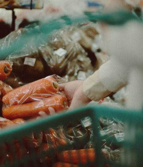 小高ストアの野菜コーナーで人参を手に取る