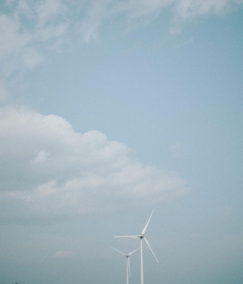 福島県南相馬の浜通りにある白い風力発電タービン2基が青空の下に立つ