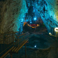 備中鐘乳穴の青くライトアップされた鍾乳石と地下水の流れの写真