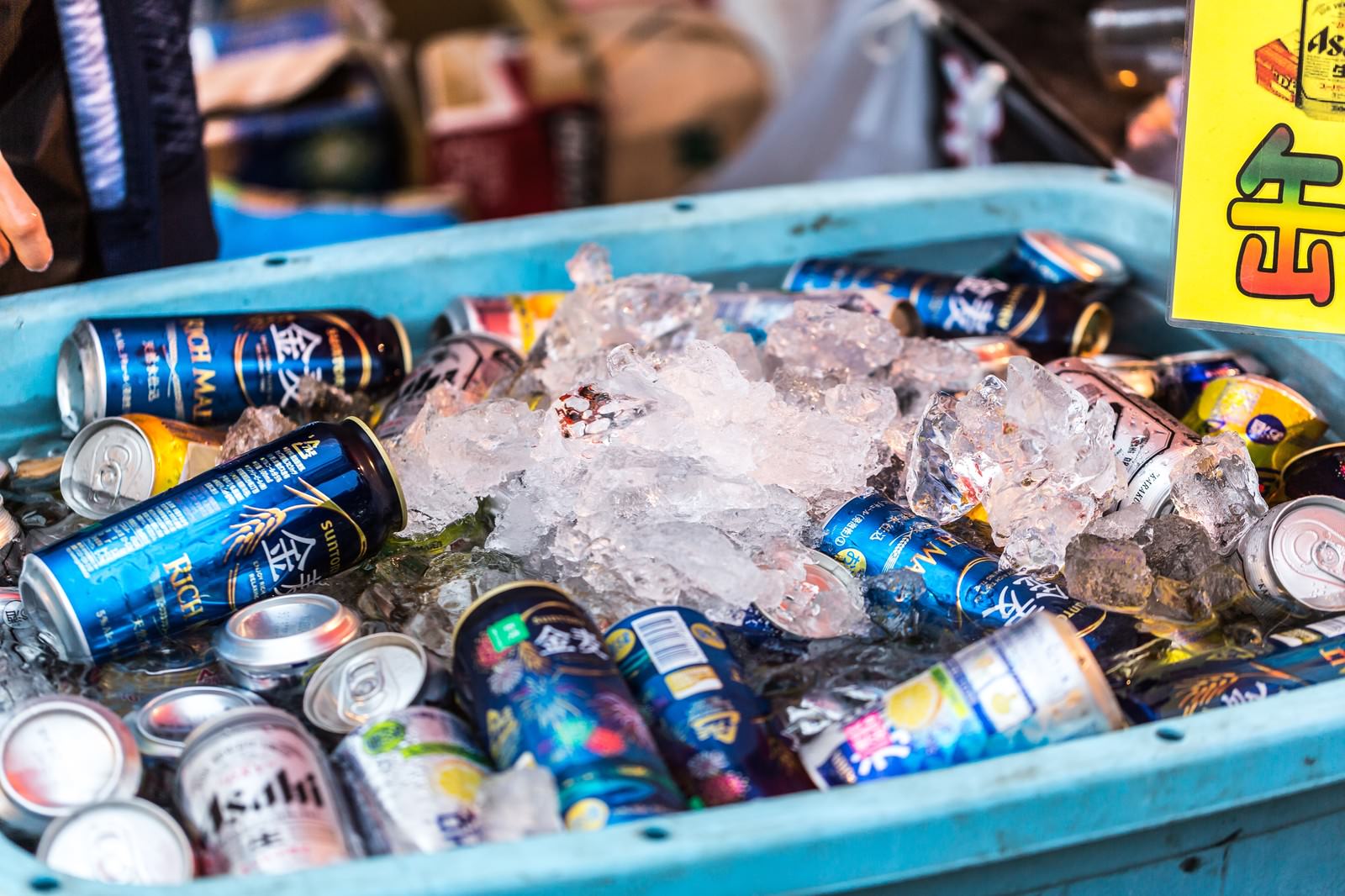 氷の入った青いコンテナで冷やされている複数の缶ビール