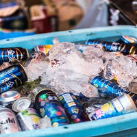 氷で冷やされた缶ビール、青いコンテナに入った冷たい飲料の写真