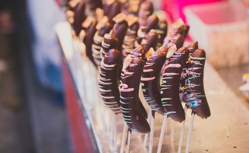 お祭りの出店に並ぶカラフルなチョコバナナの串刺しスイーツ