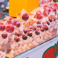 夏祭りの屋台に並ぶ赤いりんごあめのの写真