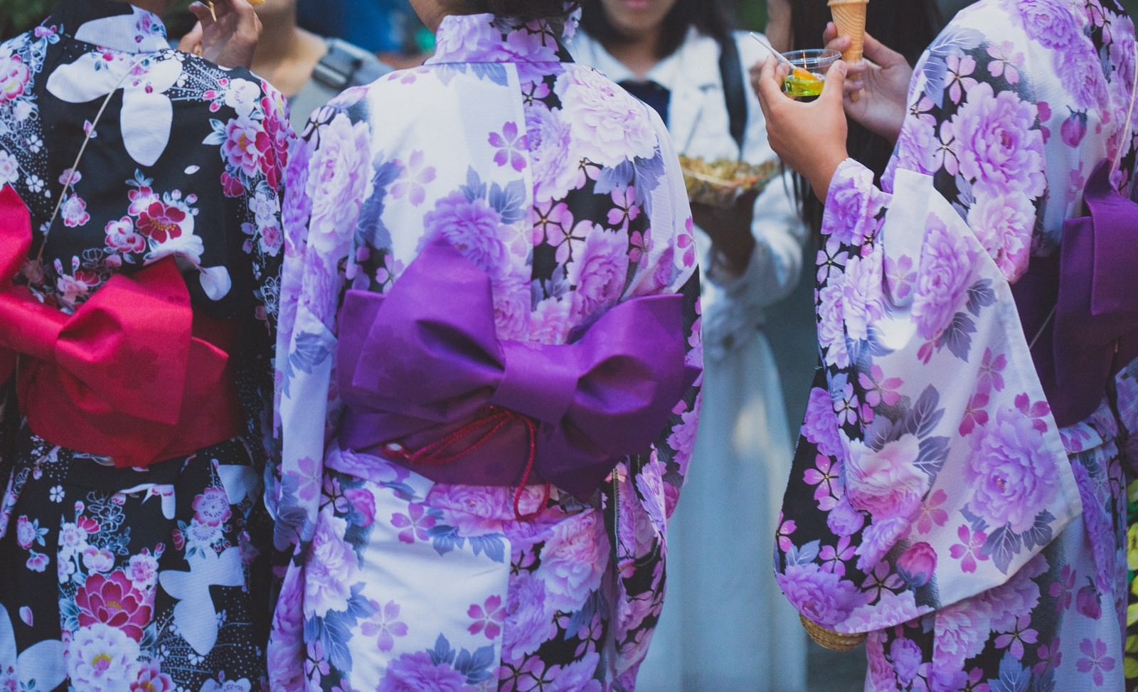 夏祭りで紫やピンクの花柄浴衣を着た複数の女性たち