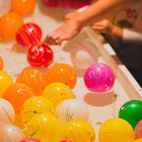 夏祭りの出店で並ぶカラフルな水風船すくいの写真