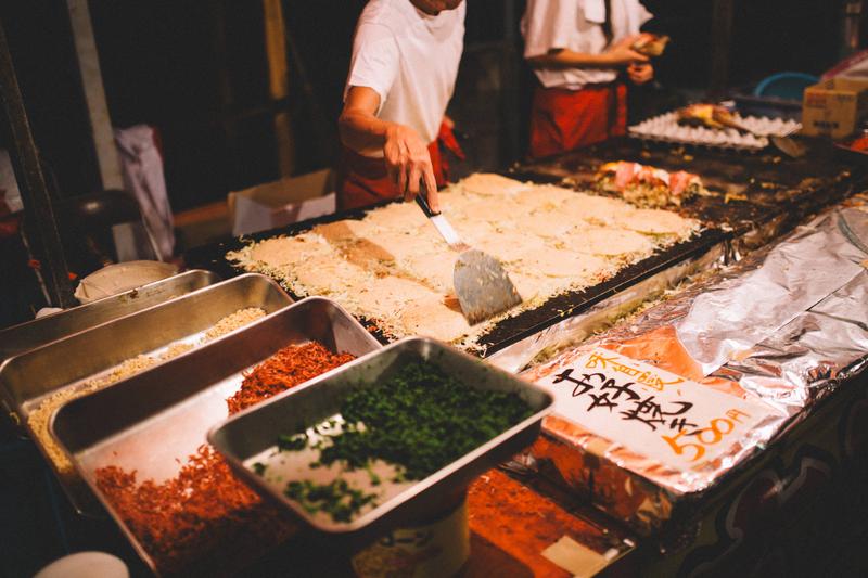 焼きそばと見せかけて広島風お好み焼きを作る屋台の大将の写真素材