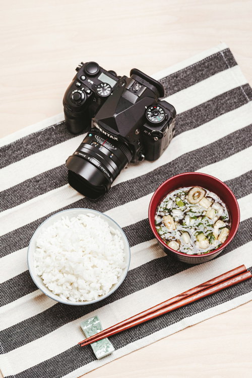一眼レフカメラと和食の朝食を並べた日常風景