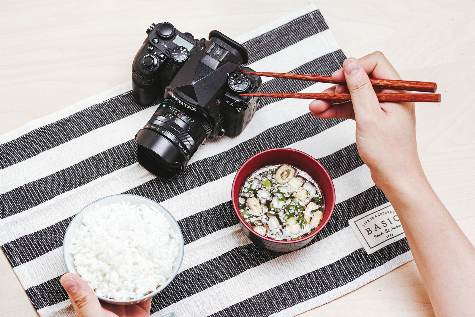 ストライプのテーブルクロス上のPENTAXデジタル一眼レフカメラと和朝食
