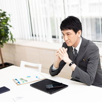 約束の時間になってもクライアントが来ない状況で悩む男性の写真