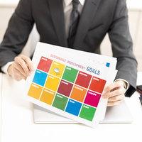 SDGs持続可能な開発目標の資料を持つビジネスマンの写真