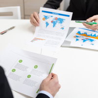 紙に印刷した資料を手に持ちながら会議がはじまるの写真