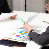 会議中、資料を使って必死に説明を繰り返す担当者の写真