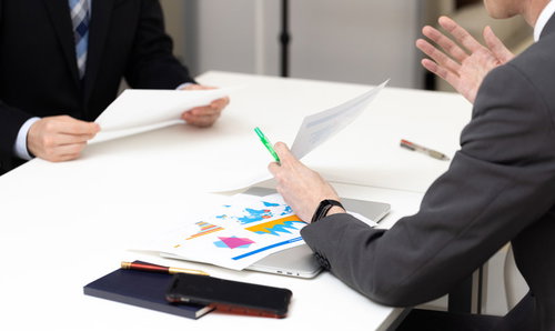 会議中、資料を使って必死に説明を繰り返す担当者