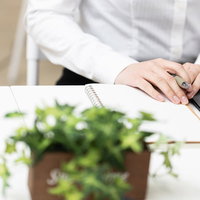 テーブルの上にノートを出して書く女性の手元の写真