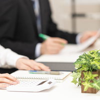 予算会議の資料と電卓を用いたビジネス打ち合わせの写真