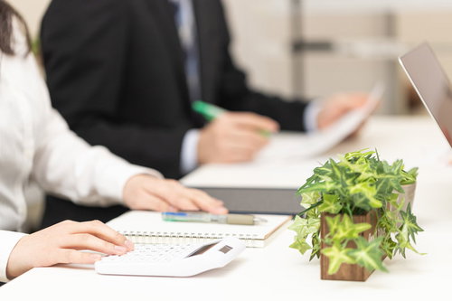 予算会議の資料と電卓を用いたビジネス打ち合わせ