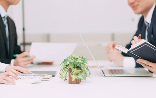 スーツ姿でテーブルを囲んで進める会議中の打ち合わせ