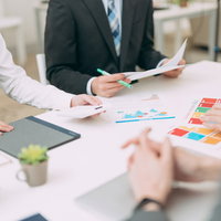 クライアントとの会議で資料を広げて打ち合わせの写真