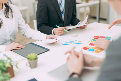 クライアントとの会議で資料を広げて打ち合わせ