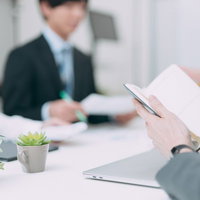 会議中にメモを開いて確認するビジネスマンの写真