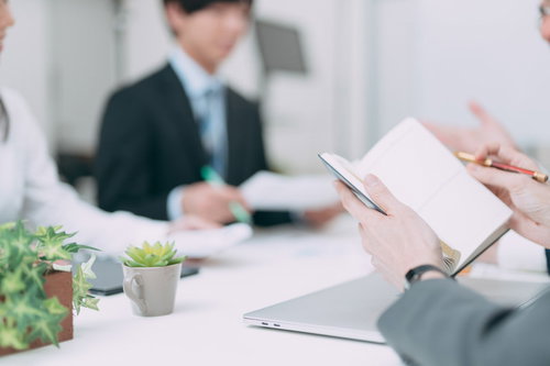 会議中にメモを開いて確認するビジネスマン