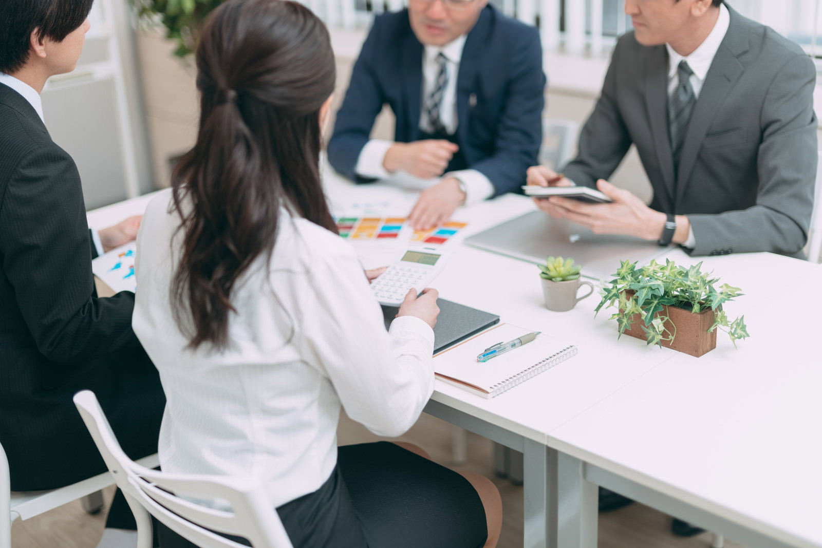 白いテーブルで資料を見ながら会議をするビジネスチーム