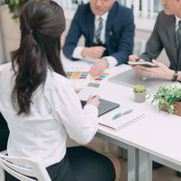 白いテーブルを囲んで資料を見ながら行う部署のチーム会議の写真