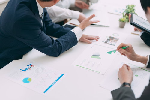 執拗に提案を繰り返す営業マンと会議中の資料検討