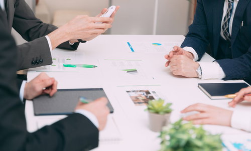 テーブルを囲んで資料を確認する会議室でのビジネスマン