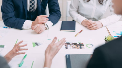 課題について資料を前に真剣に議論するビジネスパーソン