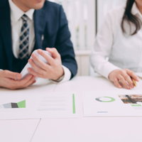 資料を見ながら検討する上司と部下の女性との打ち合わせの写真