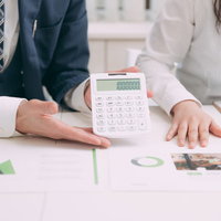 今回のコンサルフィーはこちら、電卓で金額を確認するビジネスマンと女性の写真