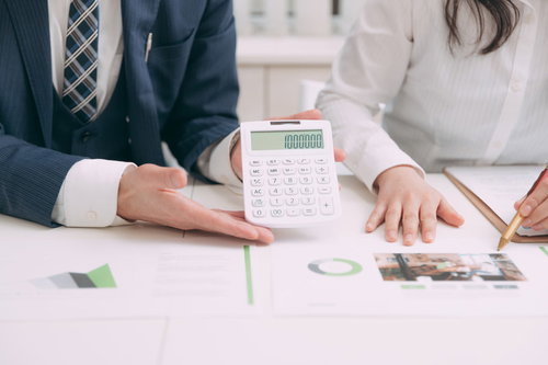 今回のコンサルフィーはこちら、電卓で金額を確認するビジネスマンと女性