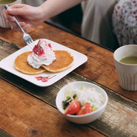 テーブルに置かれたパンケーキとお茶のカフェ風景の写真