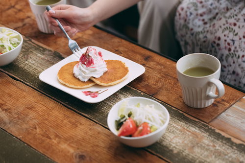 テーブルに置かれたパンケーキとお茶のカフェ風景