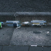 路上呑み後に散乱したゴミと空き瓶、吸い殻による路面汚染の写真