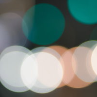 緑色とオレンジの玉ボケが重なるキラキラした光の写真