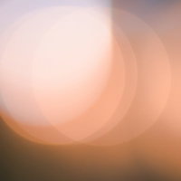 オレンジ色に重なりあう柔らかな光と暖色グラデーションの写真