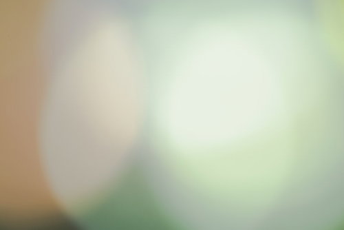 淡い薄緑に暖色光が柔らかくぼけた抽象背景