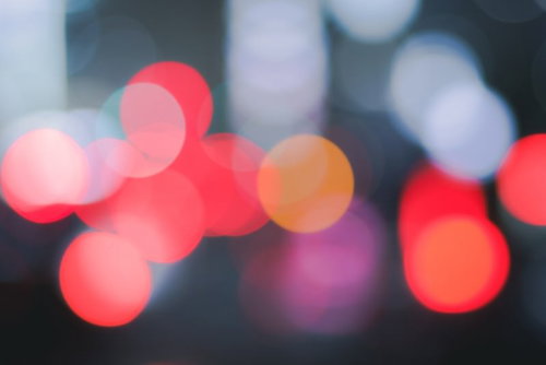 闇に浮かび上がる赤色のネオン玉ボケ、暗い背景の光