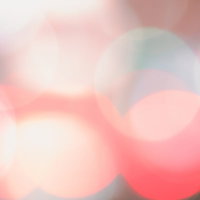 暖色系のピンクとオレンジが重なり合う柔らかい光のボケの写真