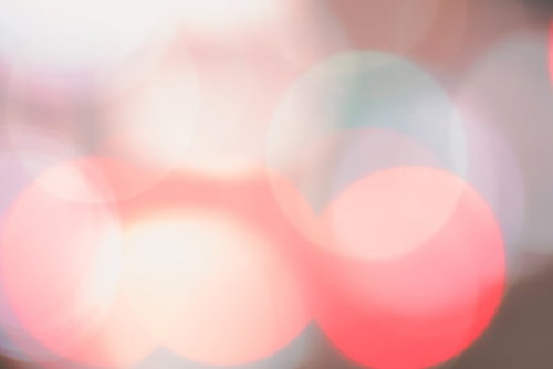 暖色系のピンクとオレンジが重なり合う柔らかい光のボケ