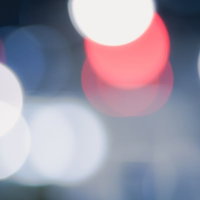 白色の玉ボケと赤い光が重なる抽象背景の写真